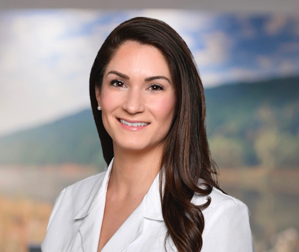 Dr. Julia Kerolus in white top in front of outdoor background