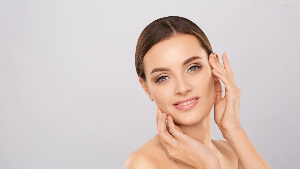 Smiling woman touching her face with her hands (model)